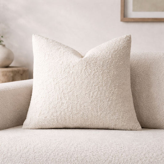 Textured beige pillow on a light-colored sofa with a neutral background