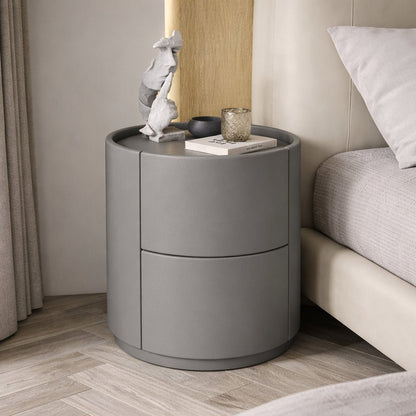 Gray round nightstand with decorative items next to a bed in a bedroom.