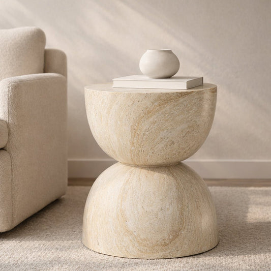 Beige stone side table with a spherical object on top in a living room setting.
