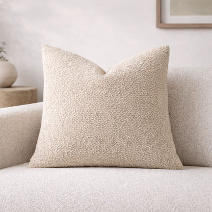 Beige textured pillow on a light gray sofa with a neutral background