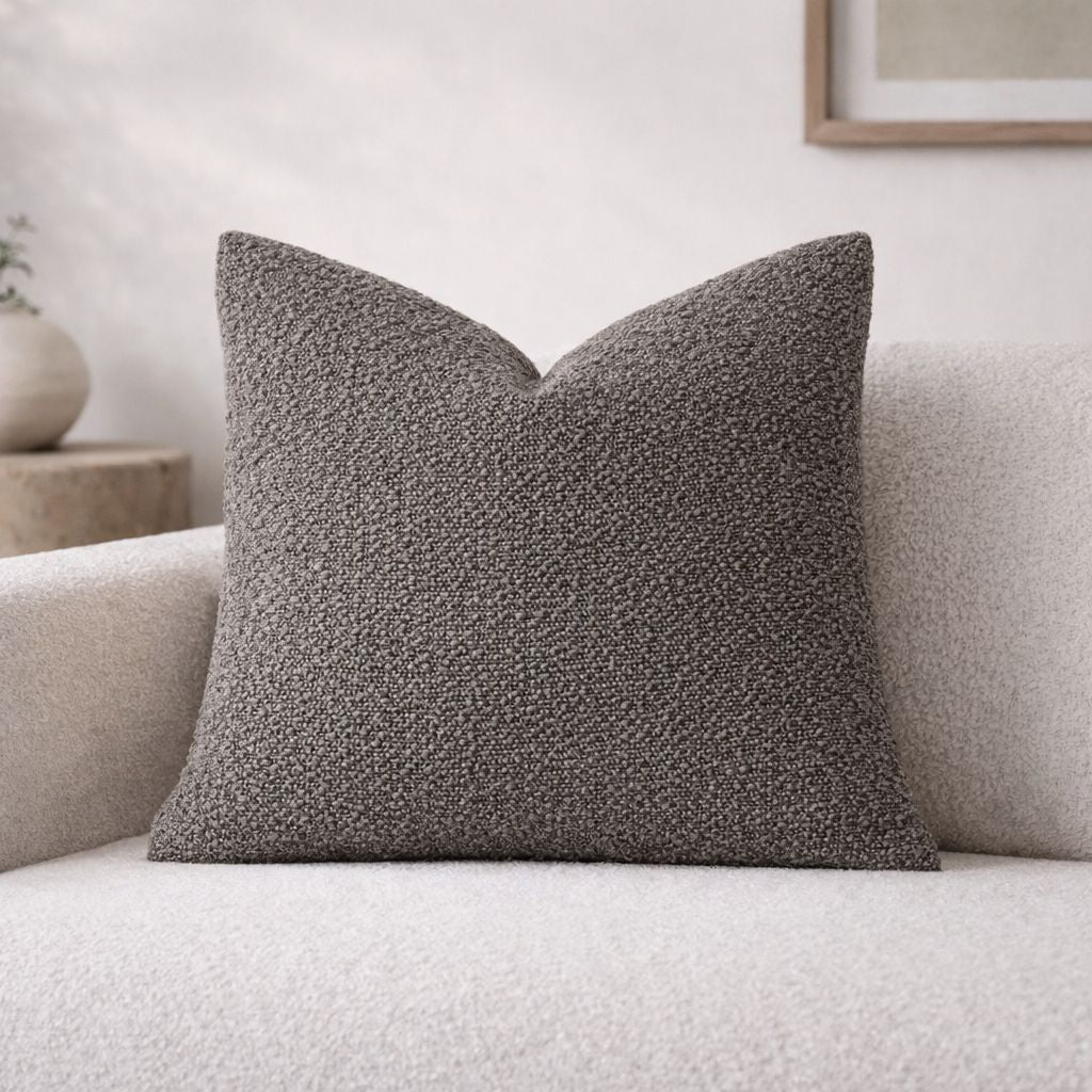 Textured gray pillow on a light-colored sofa with a neutral background