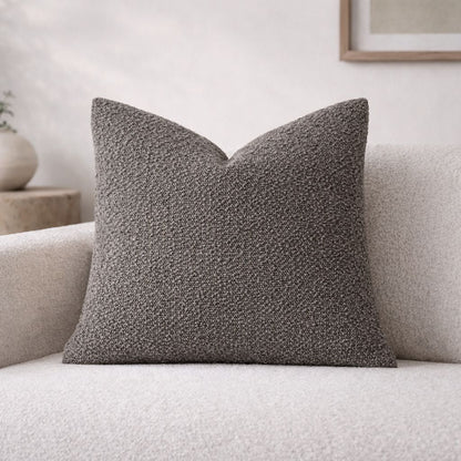 Textured gray pillow on a light-colored sofa with a neutral background