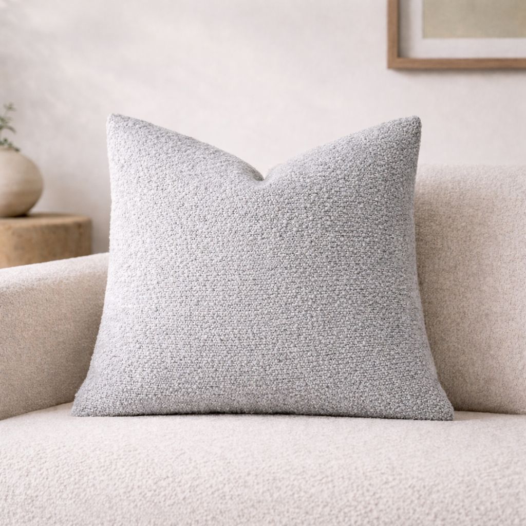 Gray textured pillow on a beige sofa with a neutral background