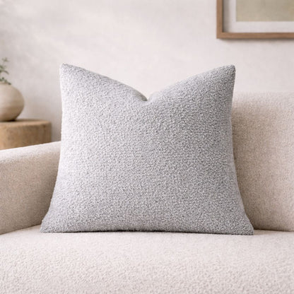 Gray textured pillow on a beige sofa with a neutral background