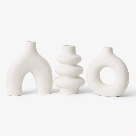 Three white ceramic vases with unique designs on a white background
