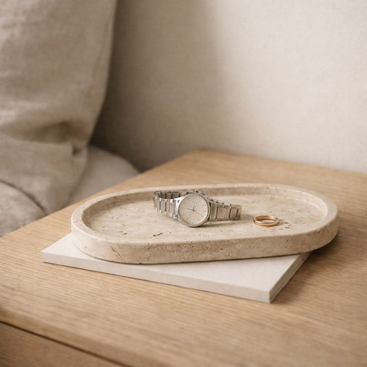 Silver watch and ring on a stone tray on a wooden surface