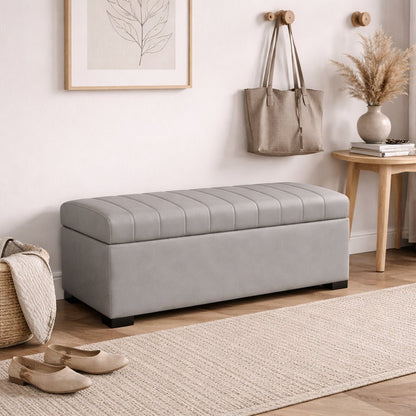 Gray storage bench in a room with a rug, shoes, and wall art.