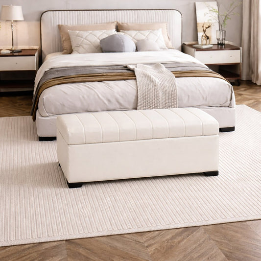 Neatly made bed with white bedding and a matching ottoman in a bedroom setting.