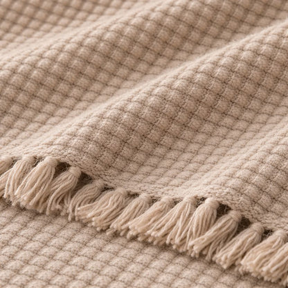 Beige textured blanket with tassels on a matching background