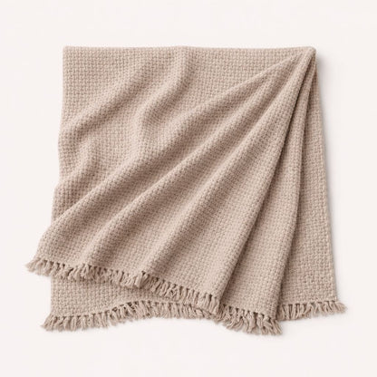 Beige woven blanket with frayed edges on a white background